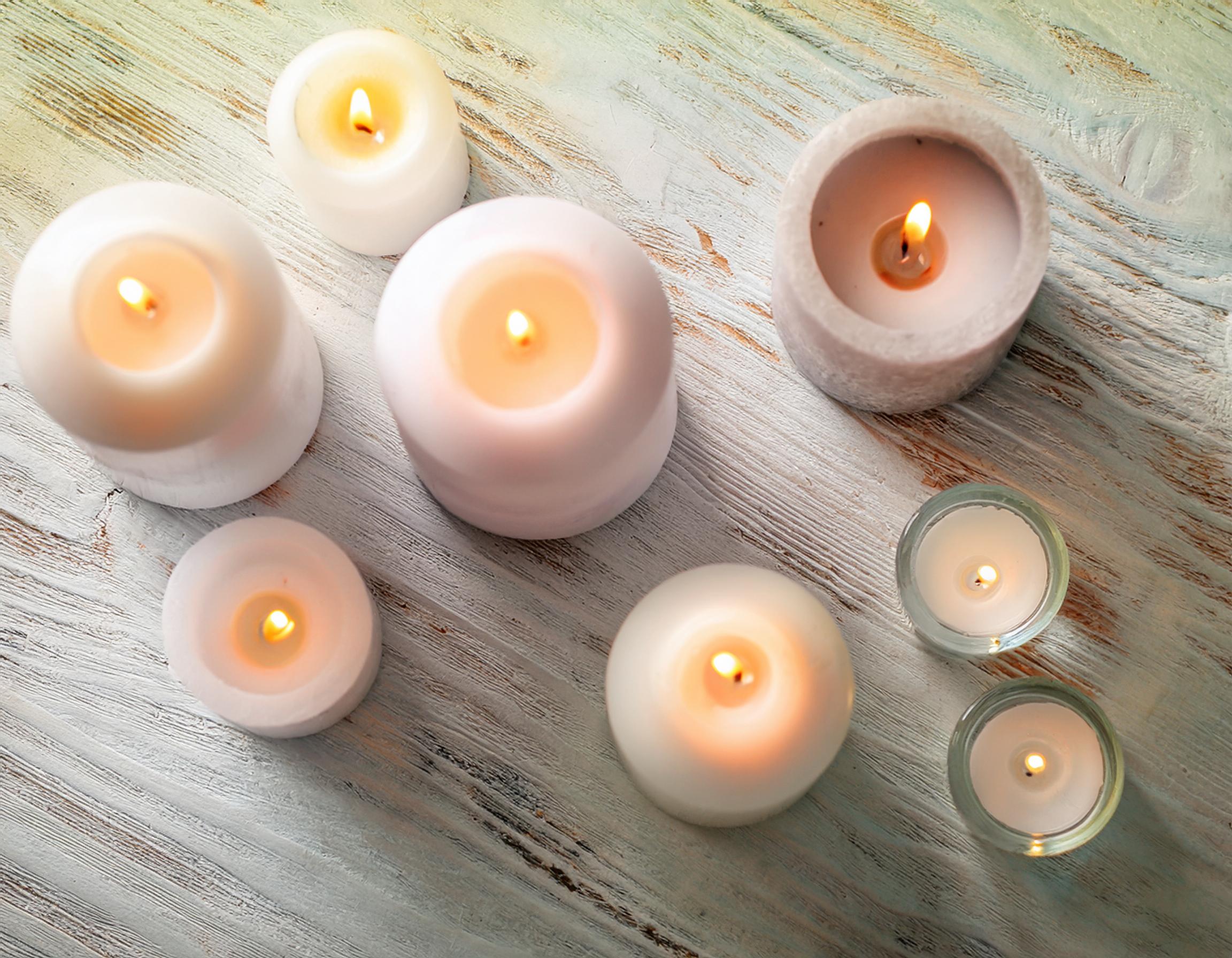 Lit pillar candles on a wooden table photographed from above.